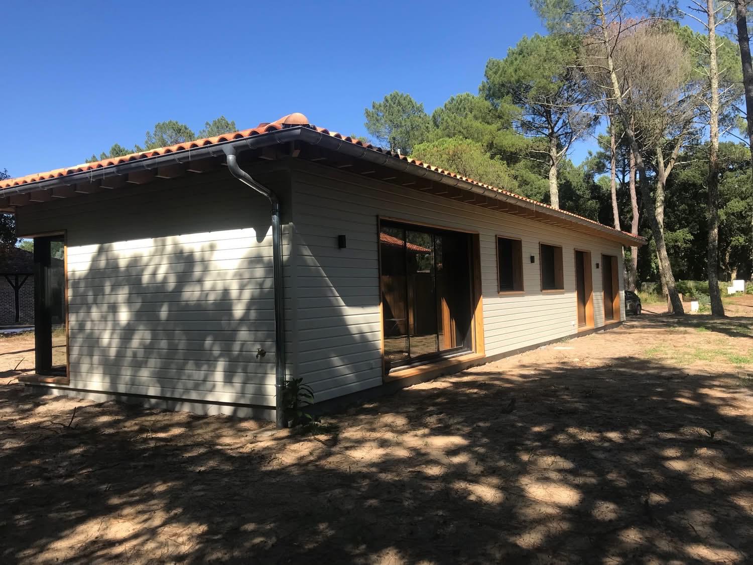 Maison à bardage bois clair dans un environnement de pins